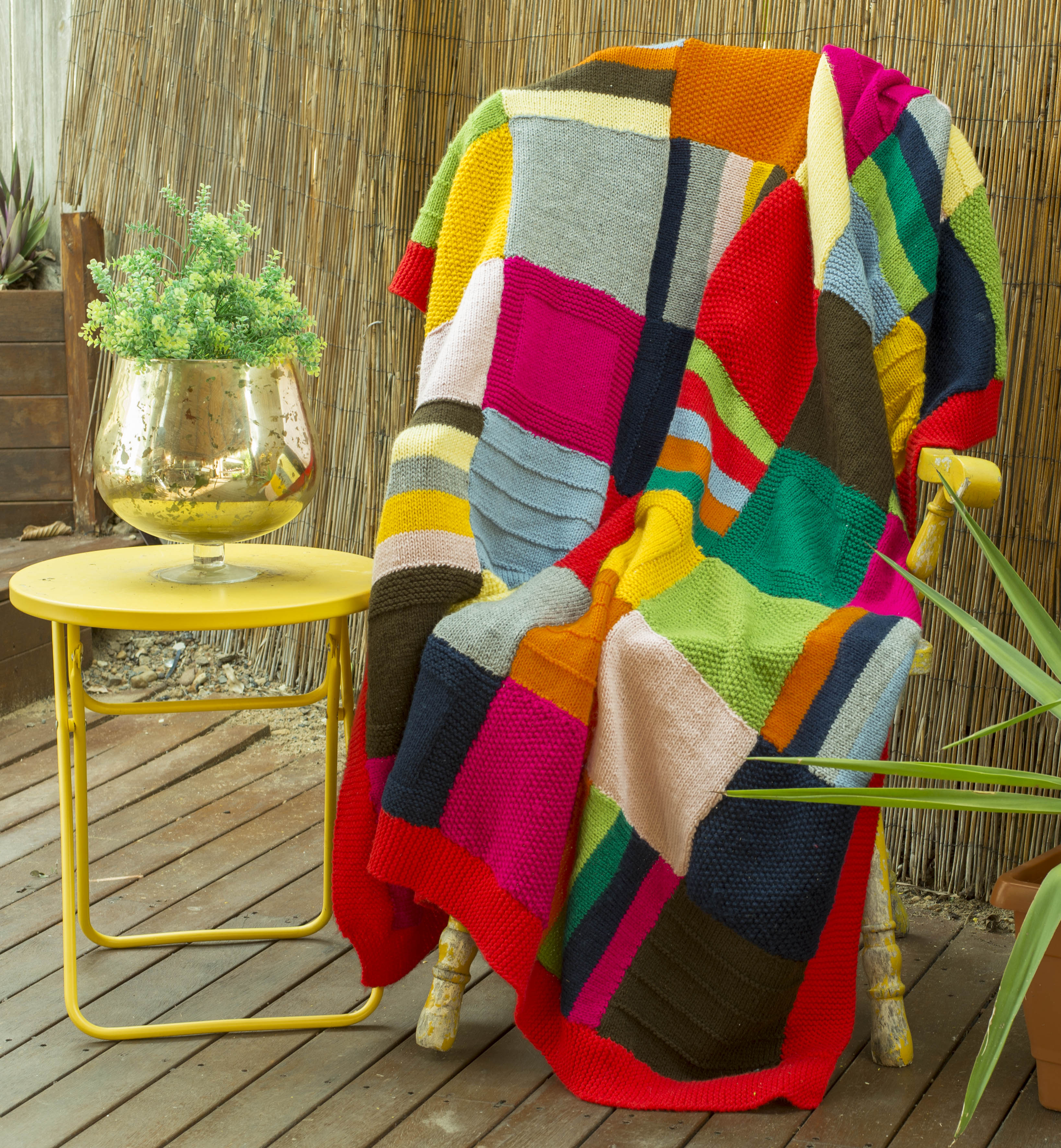 Modern, bright rug with squares and lines in shades of yellow, orange, pink, red, lime, navy, brown, grey and white, with a red trim.