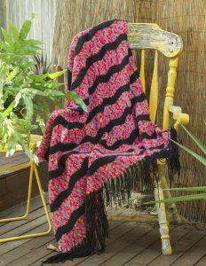 Tasselled Throw with multi-coloured small squares - like a TV test pattern - in pink, purple, yellow, red and blue, interspersed with black stripes. Order by name of "Edwina".