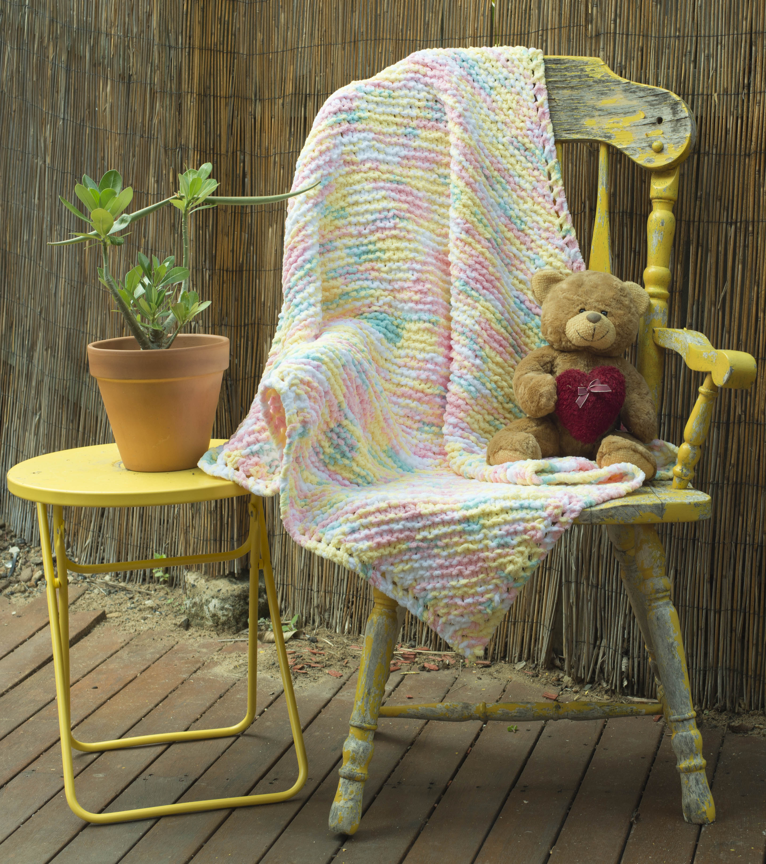 Pastel Striped Baby Blanked with Pinks, Blues, Yellows and Whites interwoven, with a teddy bear. Order by the name of "Joyce".