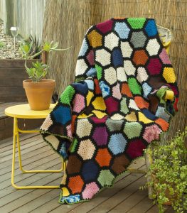 Hexagonal Rainbow Rug with navy, white, pale blue, purple, pink, orange, grey, yellow, brown and green hexagons, with a black trim. Order by name of "Wendy".