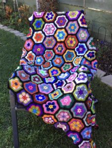 African floral rug, with shades of purple, pink, aqua, blue, yellow, orange, green and white, with black trim. Order by the name of "Susie".