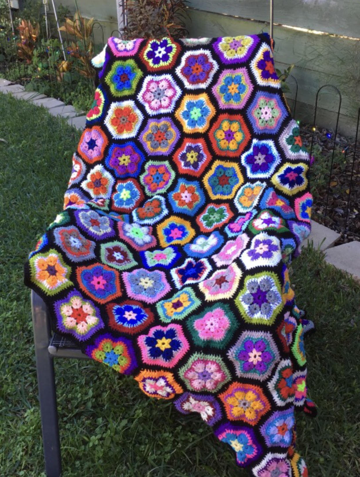 African floral rug, with shades of purple, pink, aqua, blue, yellow, orange, green and white, with black trim. Order by the name of "Susie".