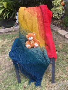 Multicoloured tasselled rug with shades of royal blue, ash blue, yellow, orange, deep pink and red.